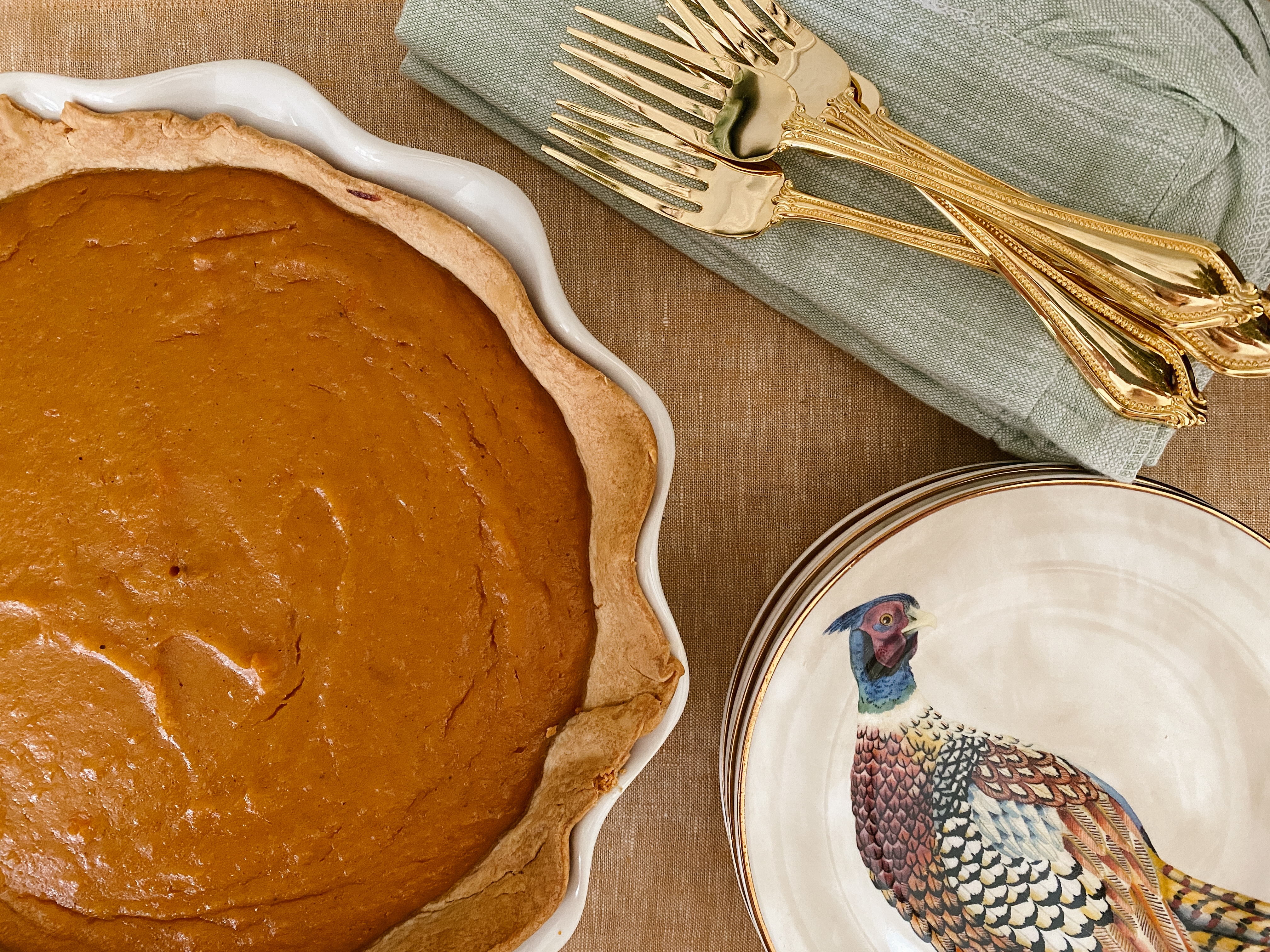 Whole Southern sweet potato pie styled with vintage silverware, linen napkins, and fall table setting.